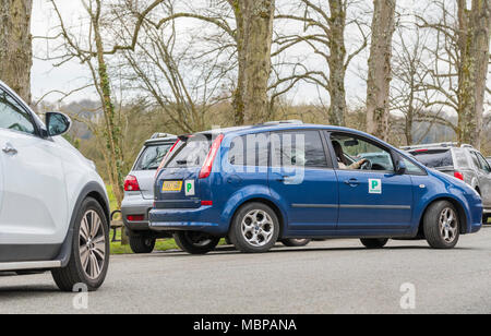 Nouveau permis probatoire affichage plaques 'P' sur une voiture, la marche arrière dans un petit parking gap en Angleterre, Royaume-Uni. Banque D'Images