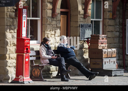 Soleil du printemps bénéficie d'une passagère assis sur un banc à la gare la vallée Severn Shrewsbury, Royaume-Uni, avec d'attente de gare pour le train suivant. Banque D'Images