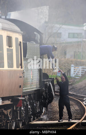 Coup d'action de l'échange de jetons, entre le pompier de l'équipe de la machine à vapeur et le signaleur de la gare, qui a lieu sur la ligne du patrimoine Severn Valley Railway, Highley, Royaume-Uni. Banque D'Images