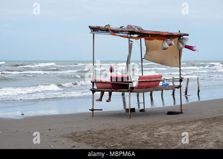 Homme assis sur un banc de la mer persique traditionnel le long de la côte caspienne. Nur, Iran Banque D'Images