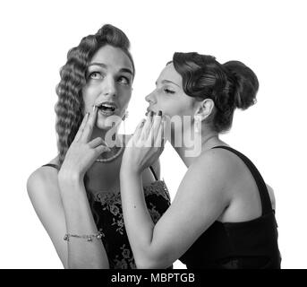 Deux jeunes femmes whispering gossip . L'émotion expressive , isolé sur fond blanc. Noir et blanc. Banque D'Images