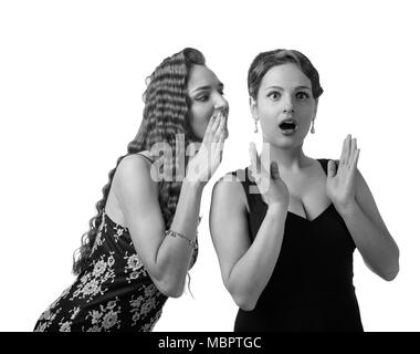 Deux jeunes femmes whispering gossip . L'émotion expressive , isolé sur fond blanc. Noir et blanc. Banque D'Images