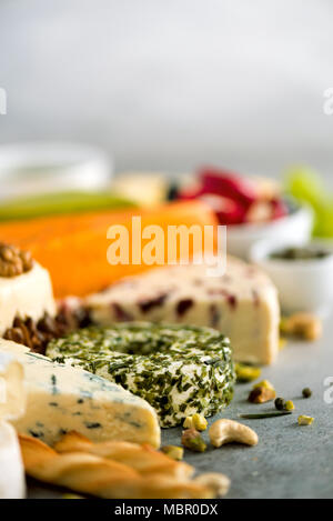 Assortiment de disque, semi-mous et les fromages aux olives, pains bâtons grissini, câpres, Raisin, sur fond de béton gris. Vue de dessus, copiez l'espace, mise à plat. Sélection de fromages apéritif assiette. Banque D'Images