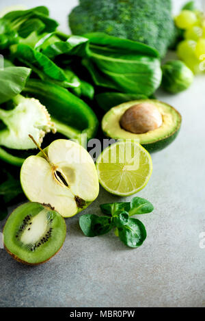 Les légumes verts et les fruits biologiques sur fond gris. Copier l'espace. Pomme verte, laitue, concombre, avocat, chou vert, citron vert, kiwi, raisin, banane, brocoli Banque D'Images