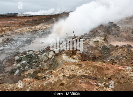 La péninsule de Reykjanes, l'Islande. Une piscine de boue bouillante dans la zone volcanique Gunnuhver. La centrale géothermique Suðurnes est dans l'arrière-plan Banque D'Images