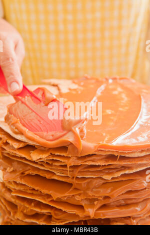 Woman Decorating Layer Cake de Dulce de Leche dans la cuisine Banque D'Images