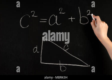 Fille main écrire théorème de Pythagore triangle rectangle avec la formule et l'école sur tableau noir avec craie blanche Banque D'Images