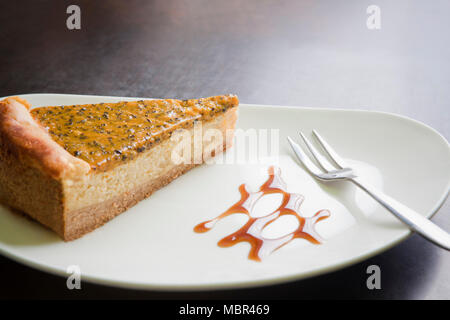 Tranche de gâteau au fromage sur un Maracuja plaque blanche ; Close up Banque D'Images