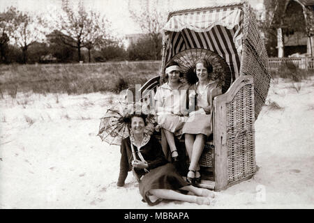 Trois femmes sur la plage, deux assis dans des chaises de plage avec parasols, locations de années 1920, mer Baltique, Allemagne Banque D'Images