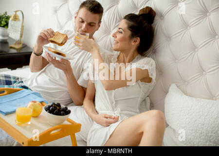 Jeune couple aimant prendre le petit déjeuner au lit Banque D'Images