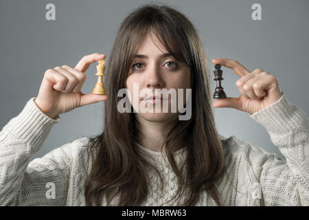 Jeune femme tenant deux noir et blanc King Pièces des échecs Banque D'Images