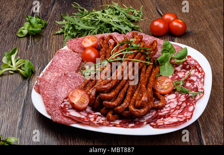 Lave de fines tranches de saucisse fumée. Les tomates et la roquette. Style rustique Banque D'Images