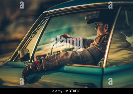 Muscle Car Cowboy dur. Les hommes de race blanche dans la trentaine d'usure de l'élégant port de prendre la route dans sa voiture de collection. West American Ride dans le style. Banque D'Images