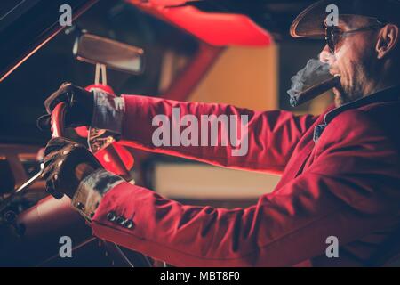 Heureux millionnaire Cowboy dans la trentaine avec brûler cigare dans le Vintage Classic Car. Rêve américain. Le gagnant chanceux de Jackpot de quitter Las Vegas. Banque D'Images