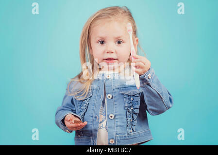 Petite fille avec une brosse à dents sur fond bleu Banque D'Images