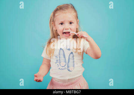 Petite fille avec une brosse à dents sur fond bleu Banque D'Images