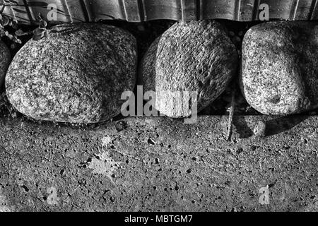 Trois grosses pierres dans un plancher de béton sont un symbole de confiance et de tranquillité, la conception de paysage. Banque D'Images