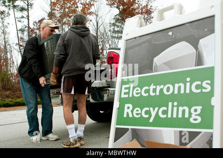 Deux hommes portent une jetée téléviseur passé un 'Electronics Recycling' signe à un événement de recyclage le 23 novembre 2013 à Lawrenceville, GA. Banque D'Images