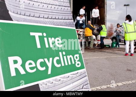 Jeunes bénévoles Aider un homme mettre les pneus à être recyclé dans un camion à Gwinnett County's America Recycles Day le 23 novembre 2013 à Lawrenceville, GA. Banque D'Images