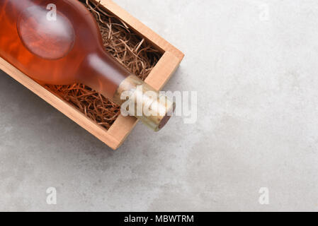 Le Zinfandel blanc, vin Blush : une bouteille de vin Rose dans une boîte en bois avec de la paille d'emballage. Élément est placé dans le coin supérieur droit avec l'exemplaire de l'espace. Banque D'Images