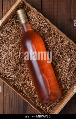 Bouteille de vin blush dans la paille d'emballage : High angle shot d'une seule bouteille dans une boîte en carton avec de la paille d'emballage. Banque D'Images