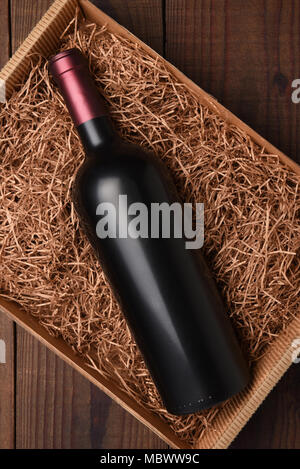 Bouteille Vin de Paille d'emballage : High angle shot d'une seule bouteille sans étiquette dans une boîte en carton avec de la paille d'emballage. Banque D'Images