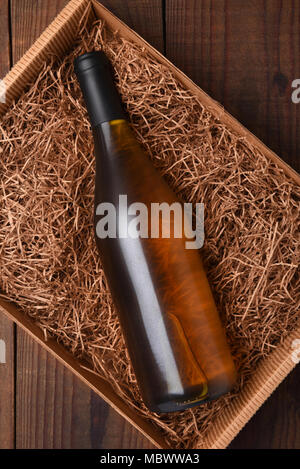 Bouteille de vin dans la paille d'emballage : High angle shot d'une seule bouteille dans une boîte en carton avec de la paille d'emballage. Banque D'Images