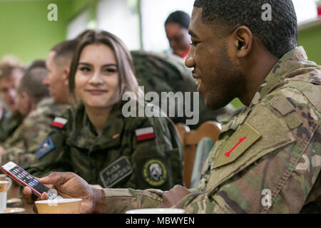 Le Cpl. Kevin Freeman (à droite), un spécialiste des ressources humaines dont le siège et l'Administration centrale, l'entreprise 2ème Armored Brigade Combat Team, 1re Division d'infanterie, de Fort Riley, Kansas, spectacles Polish high school cadets à une école locale de Rzepin, Pologne une partie de sa musique préférée lors d'une visite de classe le 15 janvier 2018. Le but de la visite était de donner aux élèves l'occasion d'en apprendre plus sur l'armée américaine et son implication dans la résolution de l'Atlantique. (U.S. Photo de l'armée par la CPS. Dustin D. Biven / Mobile 22e Détachement des affaires publiques) Banque D'Images