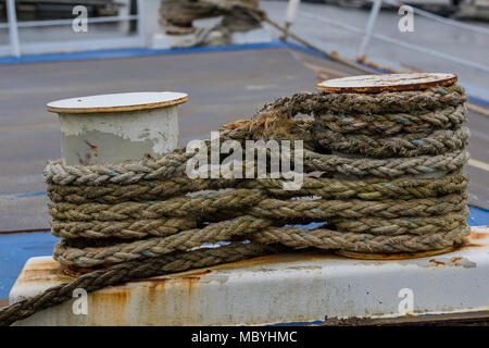 Des cordes enroulé autour de deux bornes sur le quai d'un navire dans le port qui a été attaché avec des cordes au mur. L'amarrage d'un navire enveloppé sur. Banque D'Images