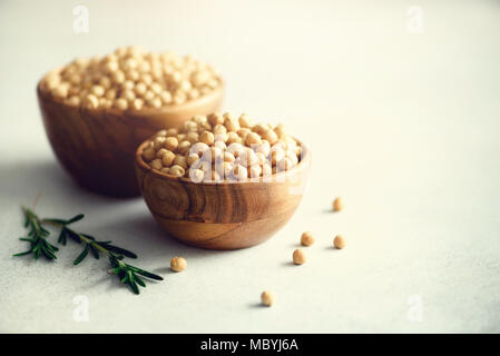 Pois chiches en matières premières biologiques bols en bois et de romarin sur fond de béton gris. Les ingrédients des aliments sains. Copier l'espace. Banner Banque D'Images