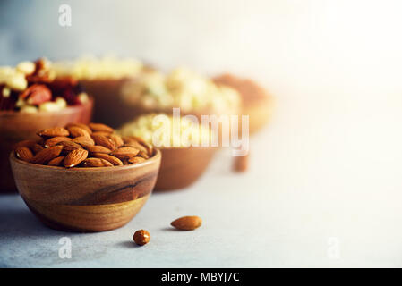 Les écrous d'amande dans un bol en bois. Mélange des aliments, l'arrière-plan, Vue de dessus de l'espace de copie, la bannière. Assortiment de noix - noix de cajou, noisettes, amandes, noix, pistaches, noix de pécan, pignons, raisins secs, arachides Banque D'Images