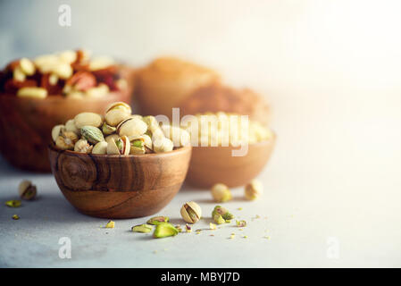 Pistaches dans bol en bois. Mélange des aliments, l'arrière-plan, Vue de dessus de l'espace de copie, la bannière. Assortiment de noix - noix de cajou, noisettes, amandes, noix, pistaches, noix de pécan, pignons, raisins secs, arachides Banque D'Images