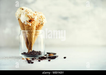 Sauce au caramel crème glacée au cornet gaufré avec les grains de café sur fond noir en gris. Concept des aliments en été, l'espace de copie. Sans gluten sains des glaces. Banner Banque D'Images