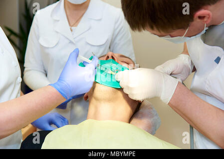 Une plaque de latex conçu pour isoler la dent du reste de la cavité orale au cours du traitement. Le dentiste fait l'injection anesthésique. Banque D'Images