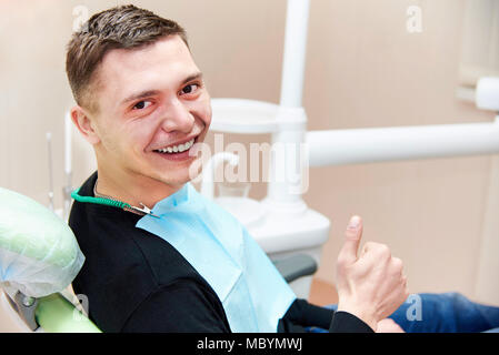 Jeune homme heureux en fauteuil dentaire montre Thumbs up. Banque D'Images