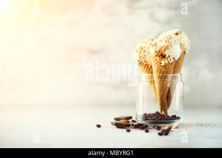 Sauce au caramel crème glacée au cornet gaufré avec les grains de café sur fond noir en gris. Concept des aliments en été, l'espace de copie. Sans gluten sains des glaces. Banner Banque D'Images