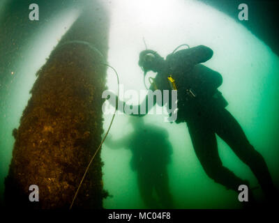 La construction de la Marine américaine 3e classe Mécanicien Lucan Jackson et de la Marine électricien de construction 2e classe Timothy Dailey, tous deux assignés à l'équipe de construction sous-marine (2) de l'UCT, enrouler une bande de coupe explosive (ECT) autour d'une pile au cours d'une plongée à Commandant, activités liées à la flotte de Sasebo (SCFA), Japon, le 16 janvier 2018. UCT-2 prévoit la construction, l'inspection, l'entretien, et la réparation des installations sous-marines et le bord de l'eau à l'appui de la Flotte du Pacifique. (U.S. Caméra de combat de la marine, spécialiste des communications de masse de photo de 1re classe Arthurgwain L. Marquez) Banque D'Images