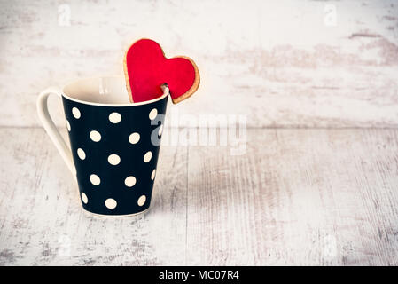 Polka dotted noir avec une tasse de café biscuits maison en forme de coeur blanc sur fond de bois. Banque D'Images