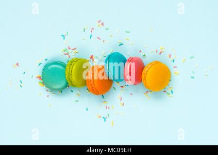 Vue de dessus de macarons colorés et saupoudre de sucre sur fond bleu. Banque D'Images