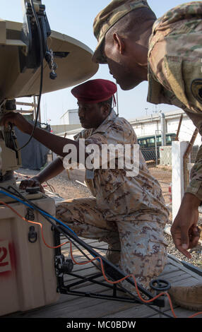 La CPS de l'armée américaine. William Reed, un opérateur de transmission multi-mainteneur et affecté à la Force opérationnelle interarmées - Corne de l'Afrique (CJTF-HOA) Direction générale des communications, les montres en tant que service membre de l'Armée de Djibouti (FAD) met en place une antenne au cours d'une de militaires à militaires Cours de change au Camp Lemonnier, Djibouti, le 8 janvier 2018. Tout au long d'une période de deux semaines, des experts de la communication a informé les membres du service djiboutien sur la façon de mettre en place, exploiter, entretenir et dépanner le matériel de réseau pour augmenter les capacités de communication entre l'Union africaine en Somalie. (U. Banque D'Images