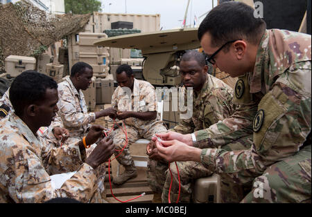 La CPS de l'armée américaine. Matthieu Jousselin, droite, un opérateur de transmission multi-mainteneur et affecté à la Force opérationnelle interarmées - Corne de l'Afrique (CJTF-HOA) Direction générale des communications, explique comment organiser le fils d'un câble d'un Djibouti Armed Forces (FAD) au cours d'un membre de militaires à militaires Cours de change au Camp Lemonnier, Djibouti, 10 janvier 2018. Tout au long d'une période de deux semaines, des experts de la communication a informé les membres du service djiboutien sur la façon de mettre en place, exploiter, entretenir et dépanner le matériel de réseau pour augmenter les capacités de communication entre l'Union africaine en som Banque D'Images