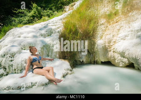 Teen girl in bikini se détend à Fossa Bianca, baleine blanche, le carbonate de calcium hot springs et des piscines en travertin Bagni San Filippo, le sud de la Toscane, JE Banque D'Images