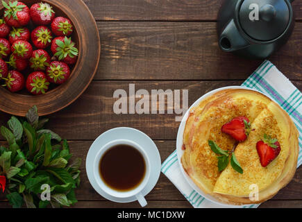 Pile de crêpes dorées avec des fraises et de la confiture de fraise, décoratives feuille de menthe. La vue de dessus Banque D'Images