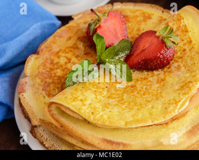 Pile de crêpes dorées avec des fraises et de la confiture de fraise, décoratives feuille de menthe. Close-up Banque D'Images