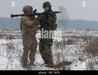 Un soldat roumain (droite) affectés à la base de la masse de l'Armée roumaine de défense aérienne, les chauves-souris noir, charge une grenade dans de roquette lanceur pour le Sgt. Stephen Lennon (à gauche), un soldat affecté au siège de l'Administration centrale et les pays fournisseurs, 3e Escadron, 2e régiment de cavalerie, de faire feu sur une plage près de la zone d'entraînement Bemowo Piskie, Pologne, le 24 janvier 2018. La multinationale, unique, composé d'Américains, Britanniques, croate et soldats roumains servir avec la 15e Brigade mécanisée polonaise comme une force de dissuasion dans le nord-est de la Pologne à l'appui de l'OTAN vers l'amélioration de la présence. Banque D'Images