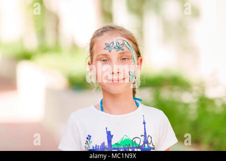 Happy little Girl with face peinture art dans le parc. Sa fête mascarade partie s'amuser, de rire. Loisirs et vacances. Banque D'Images