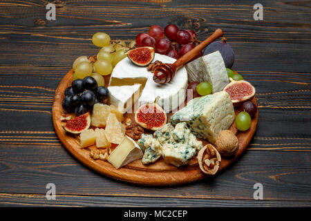 Fromage Brie sur une planche en bois avec des figues fraîches et des raisins Banque D'Images