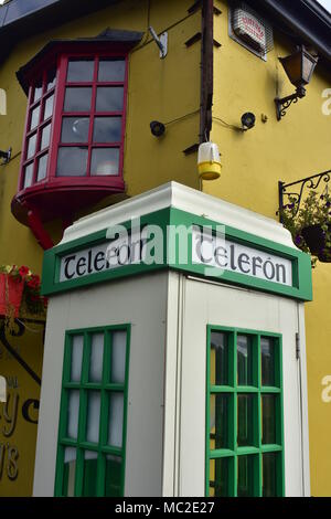 Blanc et vert vintage payer cabine téléphonique à l'Irlandais en jaune vif avec hôtel à Bunratty. Banque D'Images