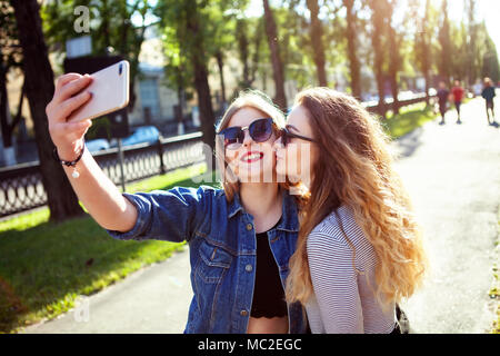 Portrait of cute joli meilleurs amis des filles, câlin et s'amuser ensemble, de baisers, de sourire, de joie, de porter des lunettes de soleil et d'été sœurs faire des photos,de leur Banque D'Images