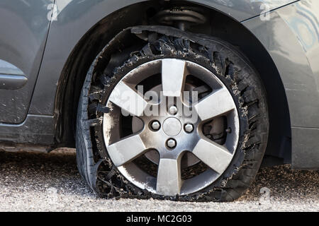 Détruit en épingle avec des pneus déchiquetés, éclatée et caoutchouc endommagé sur un suv moderne automobile. Des pneus à profil plat sur une jante en alliage, éventré Banque D'Images